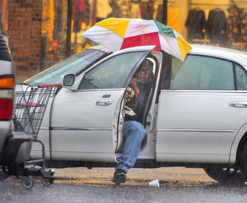 Harry Anderson tries to stay relatively dry as he maneuvers his umbrella into position before slipping out of his car during a steady rainstorm, Thursday, Dec 27, 2018, in Baton Rouge, La. He was preparing to go inside Shoppers Value on Plank Road near J.H. Cooney Street to buy some groceries, and he succeeded in staying dry, for the most part, he said. (Travis Spradling/The Advocate via AP)