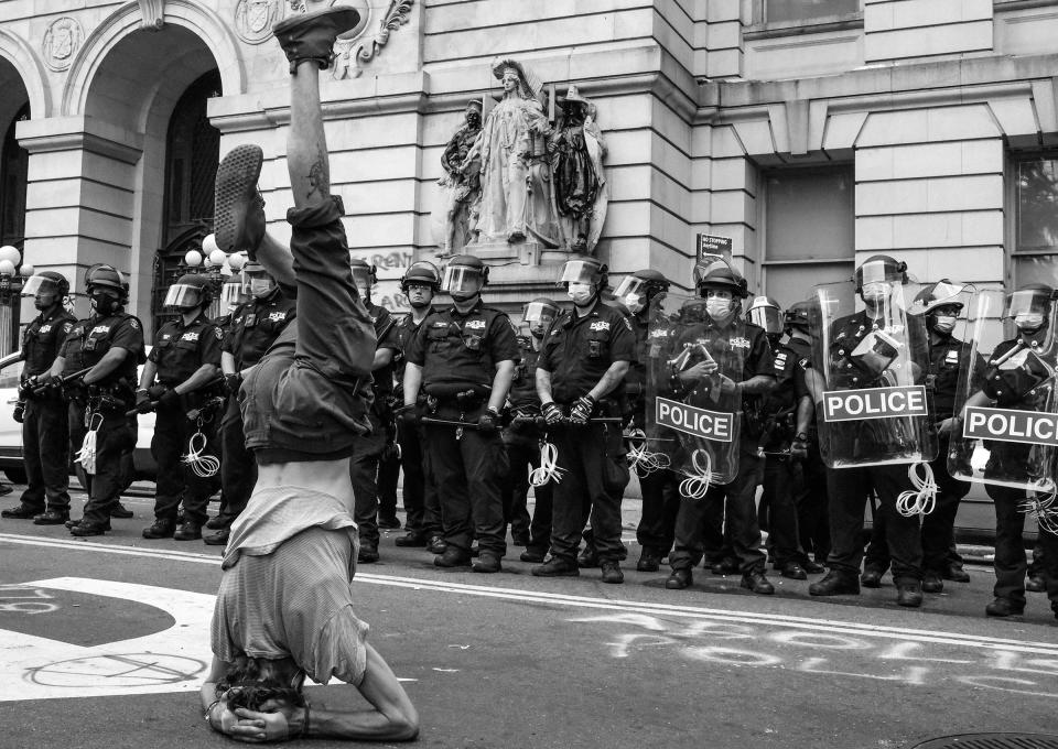 A protester stands on his head in front of a line of NYPD near City Hall during the first attempt to take over the so-called "Abolition Park," a makeshift camp in City Hall Park made up of people protesting police brutality.<span class="copyright">Clay Benskin</span>
