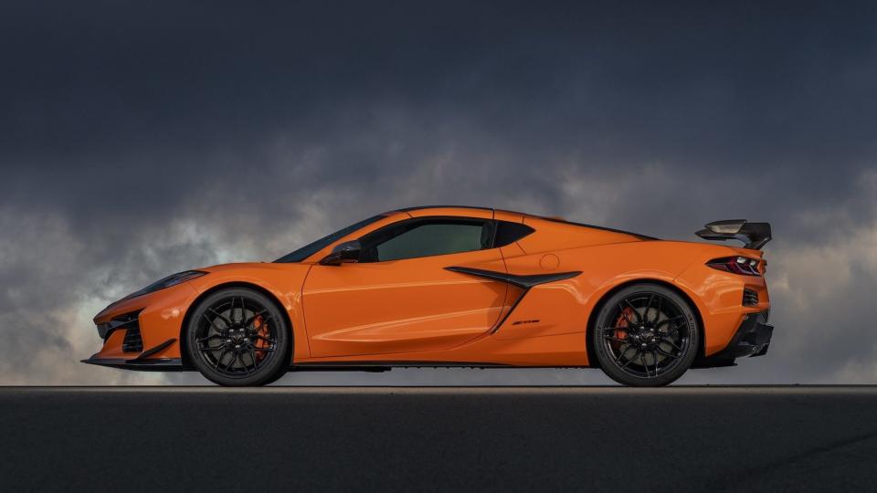 Side profile of 2023 Chevrolet Corvette Z06 in Amplify Orange Tint parked on a cloudy day.