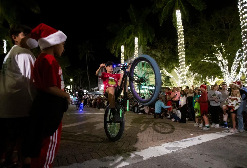 Naples BMX members pop wheelies during the Fifth Avenue South Christmas parade in Naples on Tuesday, Dec. 5, 2023.