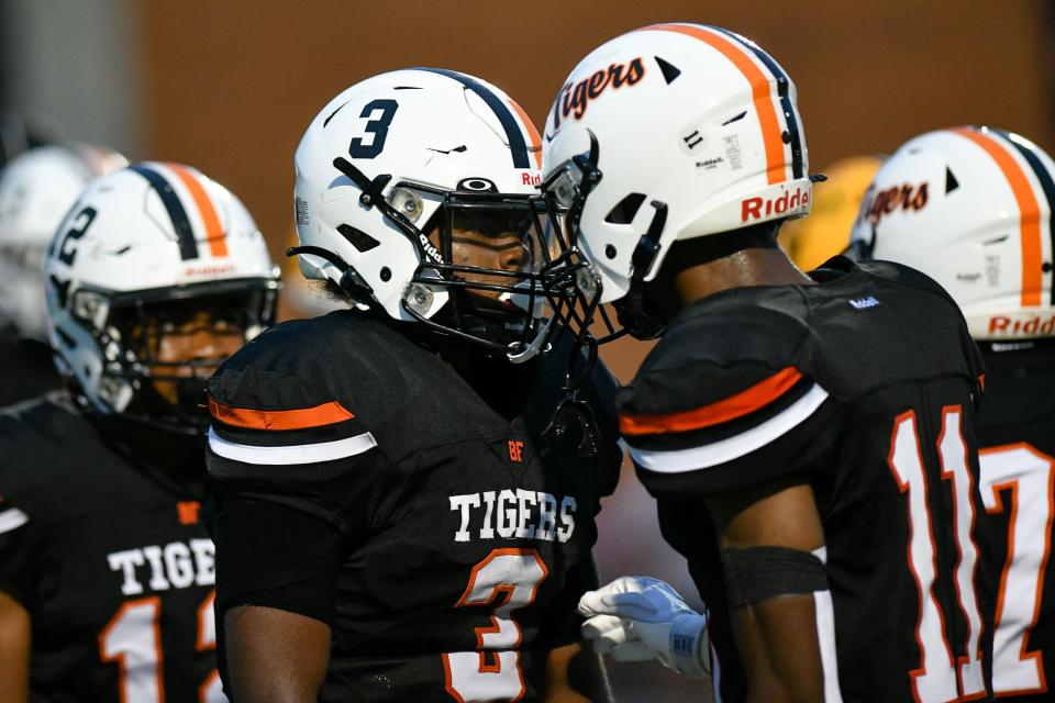 Beaver Falls' Da'Talian Beauford knocks helmets with teammate Meach Taylor after Beauford's touchdown during Friday's game against Blackhawk at Reeves Field at Geneva College.