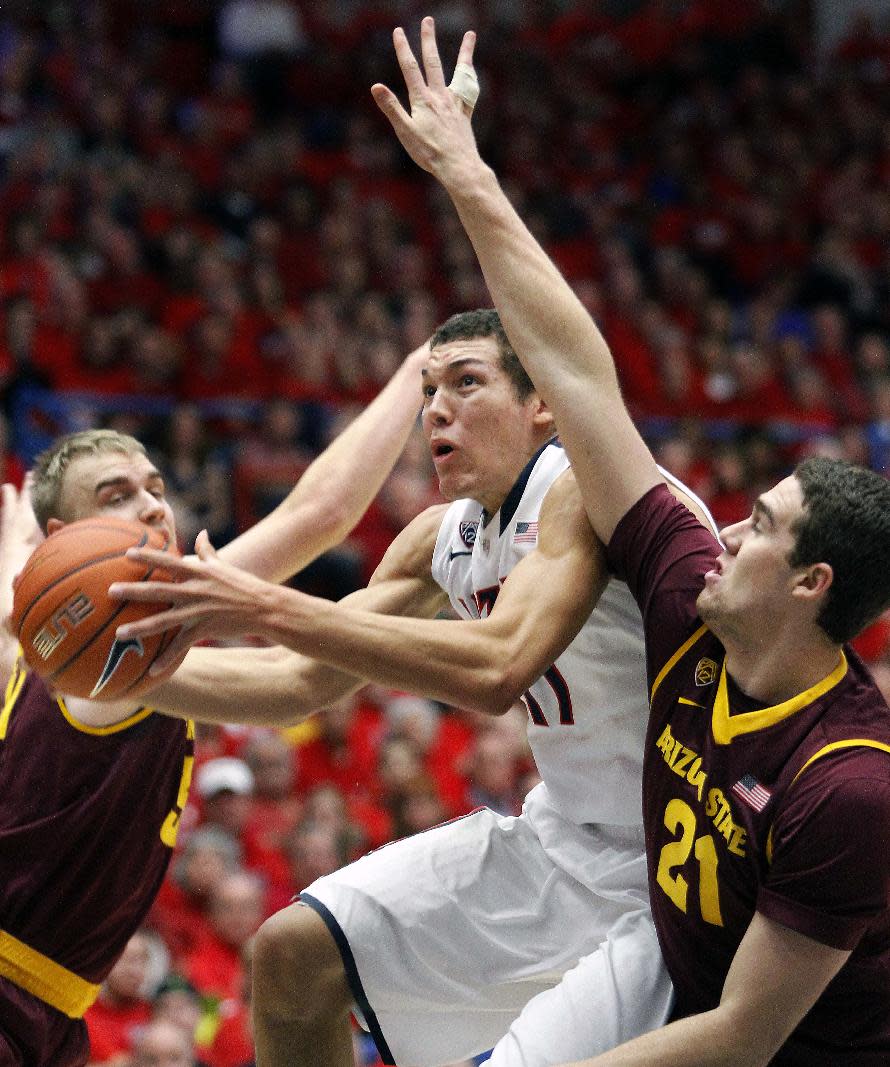 Arizona's Aaron Gordon, center, is sandwiched between Arizona's State's Jonathan Gilling, left, and Eric Koulechov (21) as he shoots for two points in the first half of an NCAA college basketball game on Thursday, Jan. 16, 2014, in Tucson, Ariz. (AP Photo/John Miller)