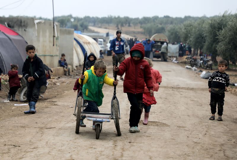 Internally displaced Syrian boys push a cart at a camp in the Northern Aleppo countryside