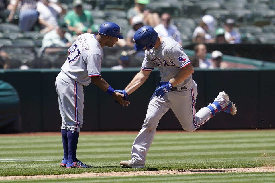 Texas Rangers' John Hicks, right, is congratulated by third base coach Tony Beasley after hitting a home run against the Oakland Athletics during the sixth inning of a baseball game in Oakland, Calif., Thursday, July 1, 2021. (AP Photo/Jeff Chiu)