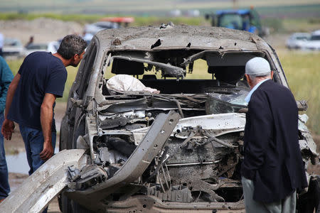 People look at a damaged car at the site of last night's explosion near the Kurdish-dominated southeastern city of Diyarbakir, Turkey May 13, 2016. REUTERS/Sertac Kayar