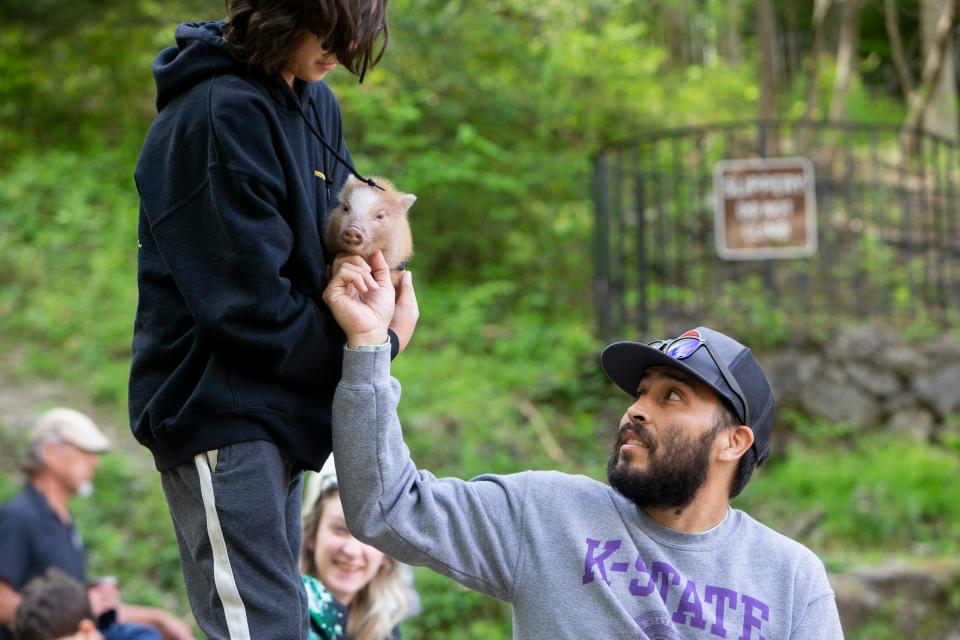 Alonzo Espinoza holds Dill, his family’s six-week-old baby pig, as his father Jorge Espinoza pets Dill before the total solar eclipse at Hot Springs National Park in Hot Springs, Arkansas on Monday, April 8, 2024. The Espinoza family came from Florida to view the eclipse.