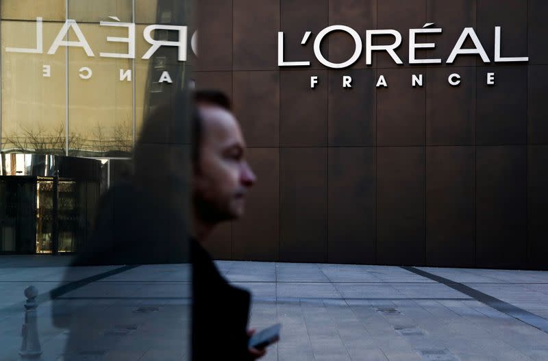 FILE PHOTO: A man walks by the logo of French cosmetics group L'Oreal in the western Paris suburb of Levallois-Perret