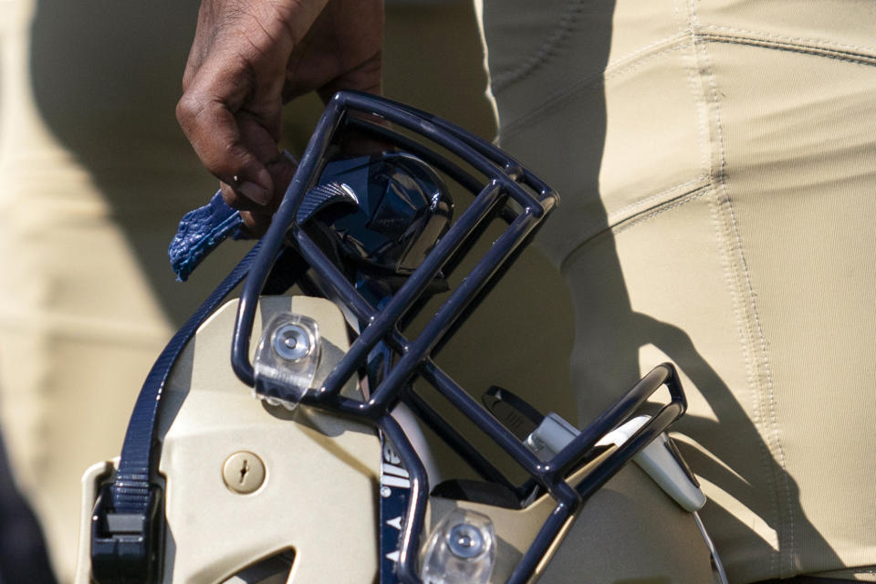 Gallaudet quarterback Brandon Washington holds a football helmet that allows play calls to show up visually on a lens inside during an NCAA college football game against Hilbert College, Saturday, Oct. 7, 2023, in Washington. Gallaudet has been playing football since 1883, when it was known as the National Deaf-Mute College, and invented the huddle roughly a decade later. The school added a drum to replace whistles in 1970, and now present-day players and coaches carry on the program's rich history by winning games and continuing to innovate, most recently the helmet developed with AT&T that helps players see play calls where hearing opponents can hear them. (AP Photo/Stephanie Scarbrough)