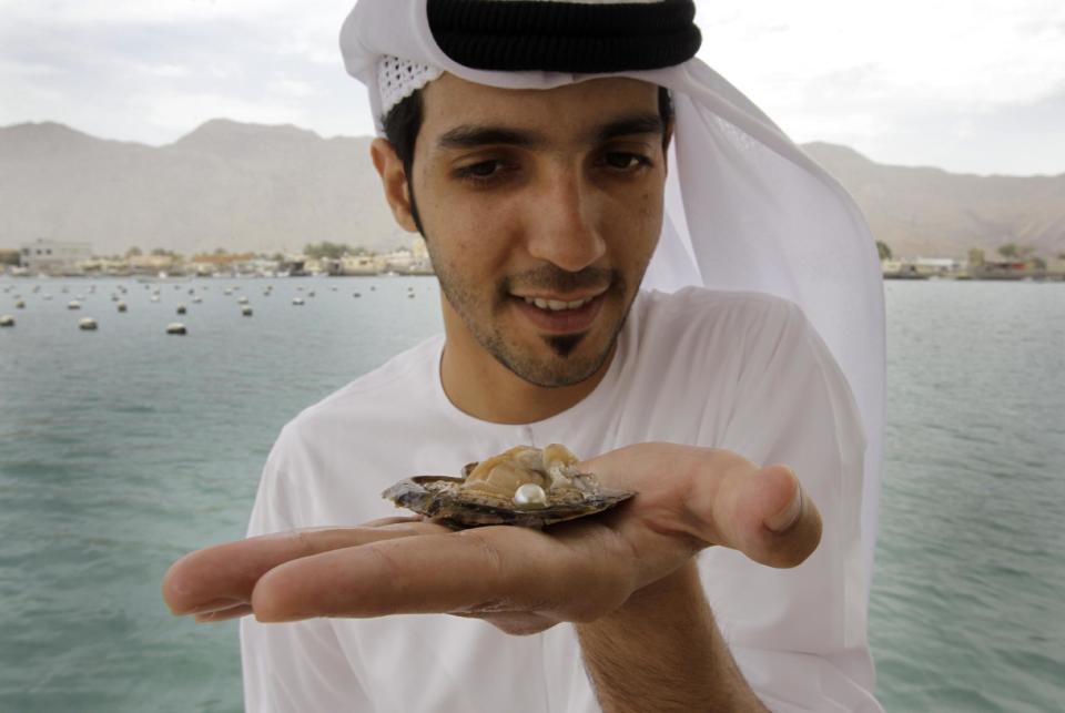 In this Wednesday, April 4, 2012 photo, Mohamed al-Suwaidi from RAK Pearls Holding holds a cultured pearl inside an oyster shell after they have collected it from the sea farm in Ras al-Khaimah, United Arab Emirates. Long before the discovery of oil transformed the Gulf, the region's pearl divers were a mainstay of the economy. Their way of life, however, also was changed forever after Japanese researchers learned how to grow cultured pearls in 1930s. Now a collaboration between pearl traders in Japan and the United Arab Emirates had brought oyster farming to the UAE for the first time. (AP Photo/Kamran Jebreili)