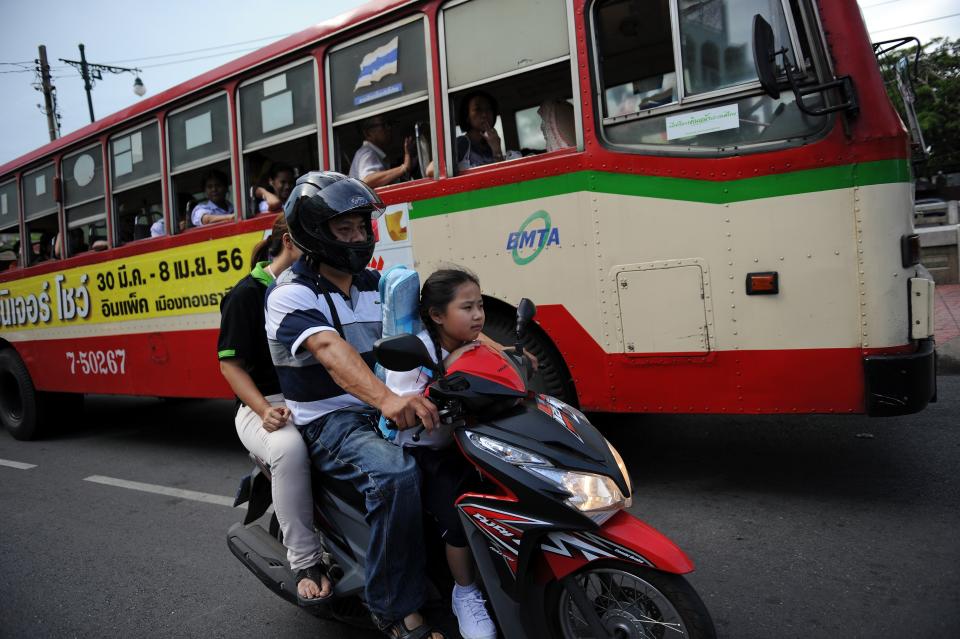 Seven-year-old Thai student Chamaya Pamutito rides a scooter as she travels back from school with her father and mother in Bangkok on June 6, 2013. 