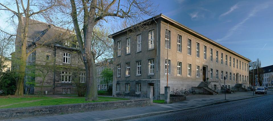 A two story stone building with trees in the foreground.