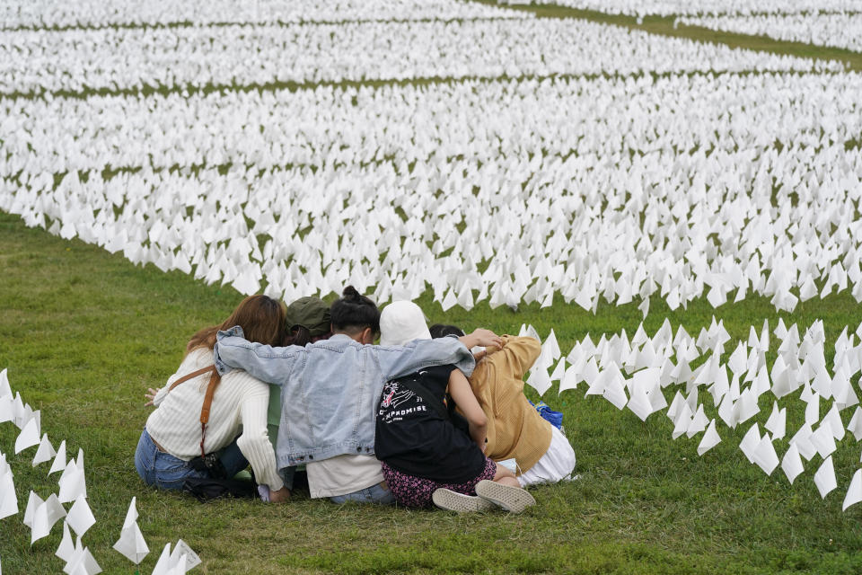 FILE - In this Sept. 21, 2021, file photo, visitors sit among white flags that are part of artist Suzanne Brennan Firstenberg's "In America: Remember," a temporary art installation to commemorate Americans who have died of COVID-19, on the National Mall in Washington. Firstenberg was struck by how strangers connected in their grief at the installation, which ended Oct. 3. (AP Photo/Patrick Semansky, File)