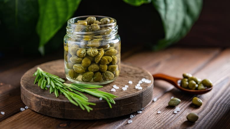 jar of capers on wooden round