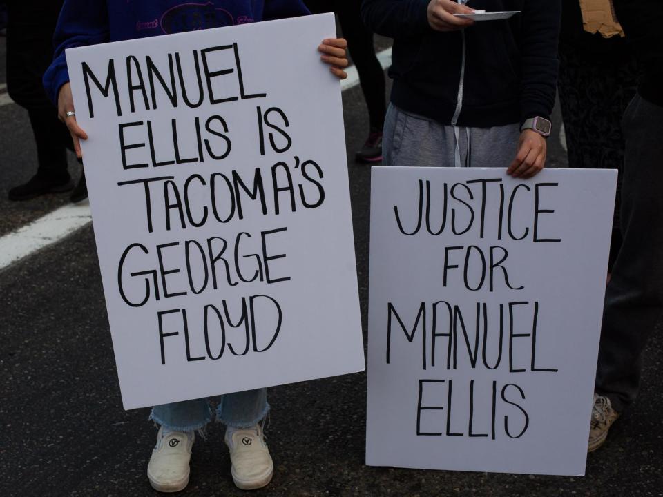 People hold signs during a vigil for Manuel Ellis, a black man whose March death while in Tacoma Police custody was recently found to be a homicide: (Getty Images)