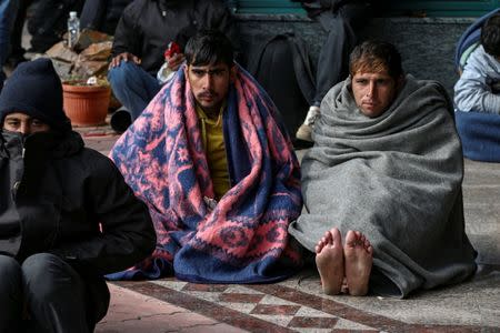 Refugees and migrants try to warm themselves as they take a break at a petrol station before abandoning their trek to the Hungarian border, in the town of Indjija, Serbia October 5, 2016. REUTERS/Marko Djurica