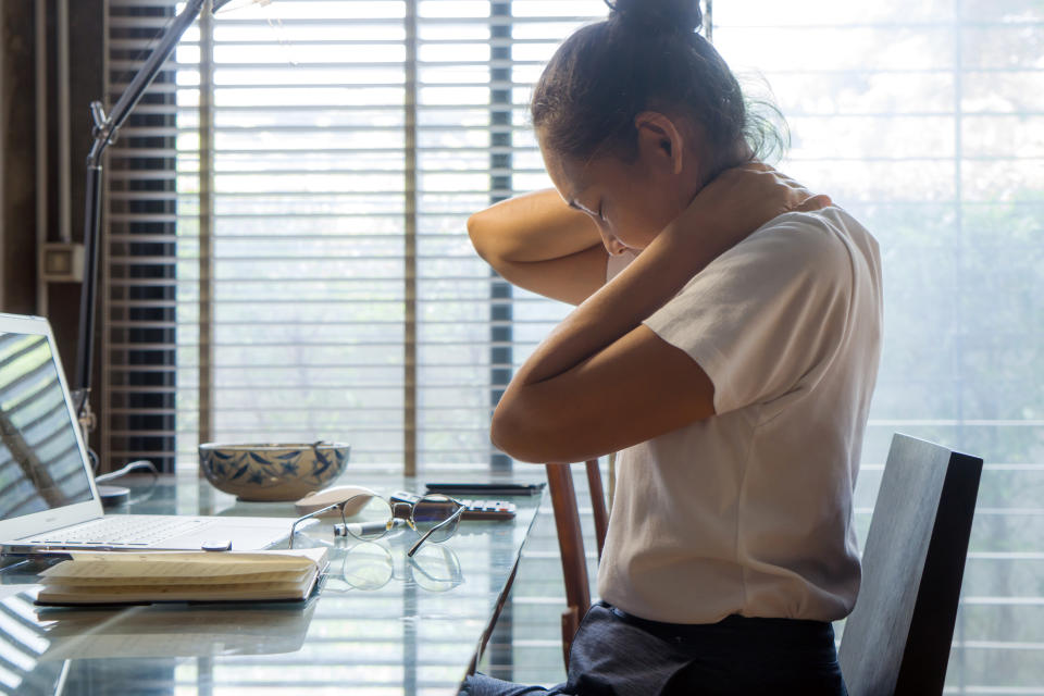 Woman holding her neck in pain while working on computer at home. Healthcare and problem concept office syndrome.