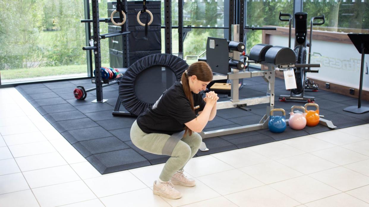  Personal trainer from Fitness Superstore demonstrates a squat with the aid of a resistance band. 