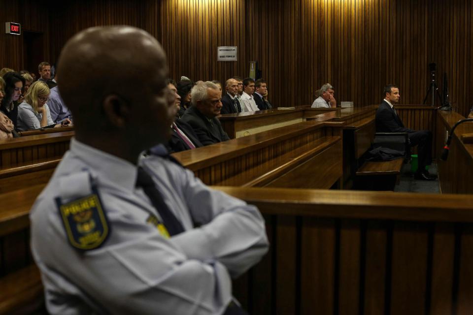 Oscar Pistorius, right, sits in the dock and listens to cross questioning about the events surrounding the shooting death of his girlfriend Reeva Steenkamp, in court during his trial in Pretoria, South Africa, Tuesday, March 11, 2014. Pistorius is charged with the shooting death of Steenkamp, on Valentines Day in 2013. (AP Photo/Kevin Sutherland, Pool)