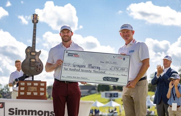 Grayson Murray and PGA pro Brandt Snedeker show off the $270,000 check Murray eanred for winning the Simmons Bank Open for the Snedeker Foundation at The Grove Sunday.