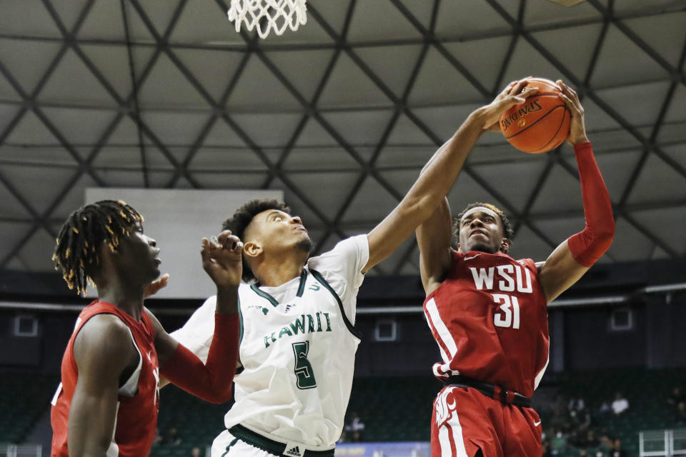 Washington State guard Kymany Houinsou (31) grabs a rebound away from Hawaii forward Bernardo da Silva (5) during the second half of an NCAA college basketball game, Friday, Dec. 23, 2022, in Honolulu. (AP Photo/Marco Garcia)