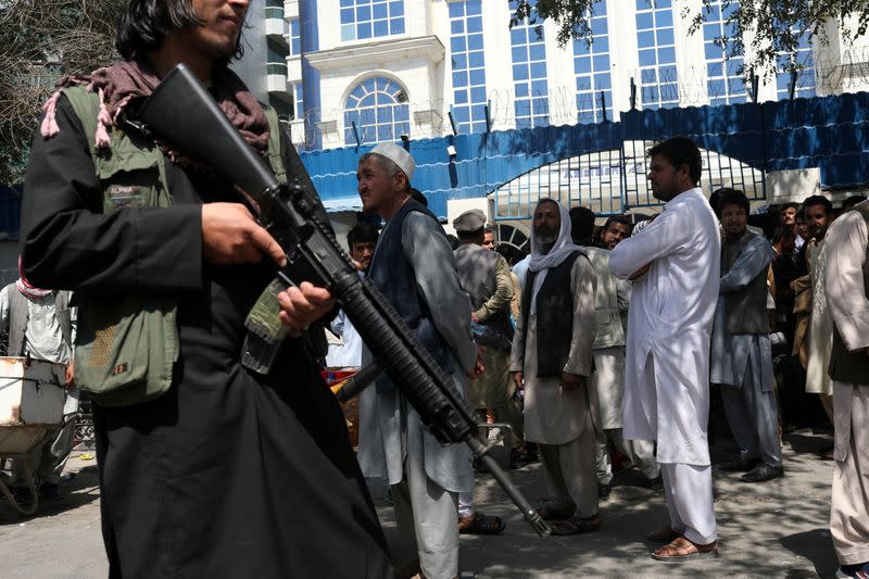 FILE PHOTO: A Taliban security member holding a rifle ensures order in front of Azizi Bank in Kabul