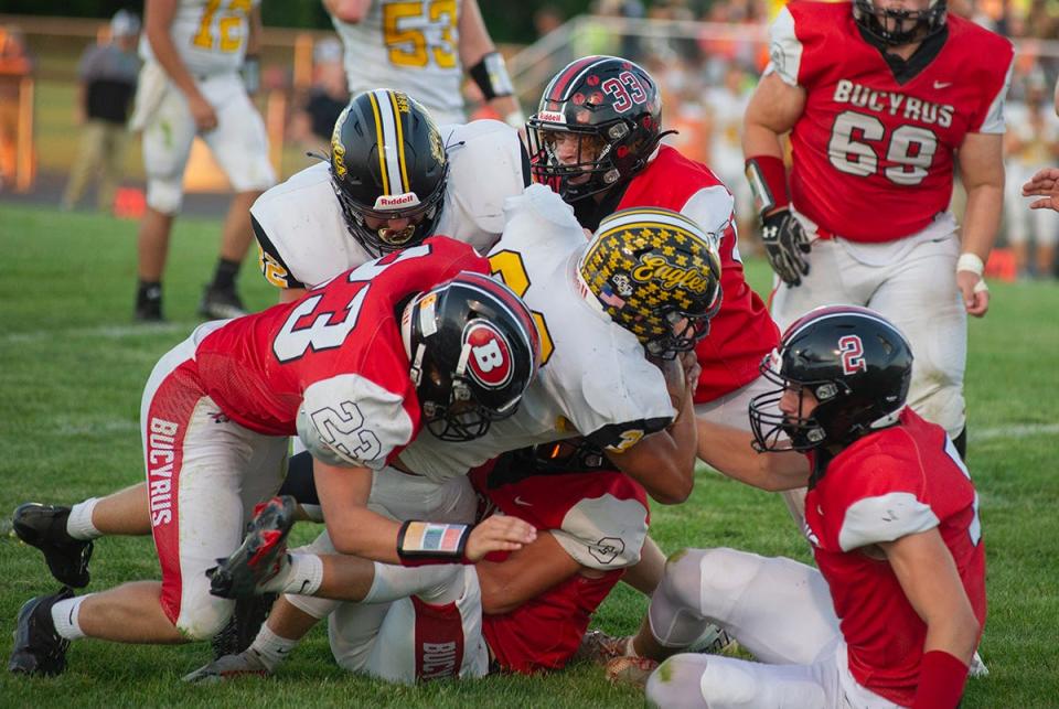 Colonel Crawford's Matt Clinard is brought down by Bucyrus' Blayne Barto and Jacob Green.