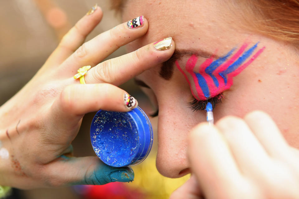 BERLIN, GERMANY - JULY 21: An attendee gets her face painted with glitter at the second annual Hipster Olympics on July 21, 2012 in Berlin, Germany. With events such as the "Horn-Rimmed Glasses Throw," "Skinny Jeans Tug-O-War," "Vinyl Record Spinning Contest" and "Cloth Tote Sack Race," the Hipster Olympics both mocks and celebrates the Hipster subculture, which some critics claim could never be accurately defined and others that it never existed in the first place. The imprecise nature of determining what makes one a member means that the symptomatic elements of adherants to the group vary in each country, but the archetype of the version in Berlin, one of the more popular locations for those following its lifestyle, along with London and Brooklyn, includes a penchant for canvas tote bags, the carbonated yerba mate drink Club Mate, analogue film cameras, an asymetrical haircut, 80s neon fashion, and, allegedly, a heavy dose of irony. To some in Berlin, members of the hipster "movement" have replaced a former unwanted identity in gentrifying neighborhoods, the Yuppie, for targets of criticism, as landlords raise rents in the areas to which they relocate, particularly the up-and-coming neighborhood of Neukoelln. (Photo by Adam Berry/Getty Images)