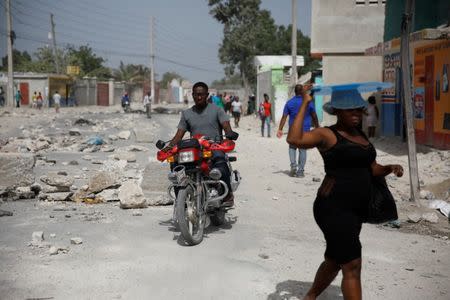 People walk along a road blocked by rocks in Croix-des-Bouquets, Haiti, July 8, 2018. REUTERS/Andres Martinez Casares
