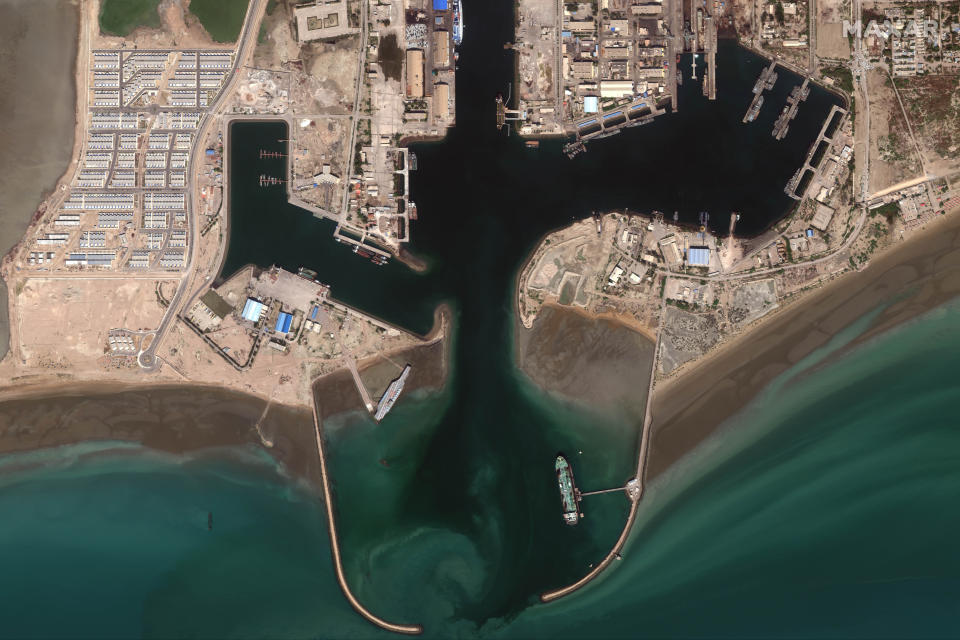 In this Feb. 15, 2020, satellite photo provided on July 27, 2020, by Maxar Technologies, a mockup aircraft carrier, center left, built by Iran is seen at Bandar Abbas, Iran, before being put to sea. Satellite photographs released Monday, July 27, showed Iran has moved the aircraft carrier out to sea likely for naval drills amid heightened tensions between Tehran and the U.S. (Maxar Technologies via AP)