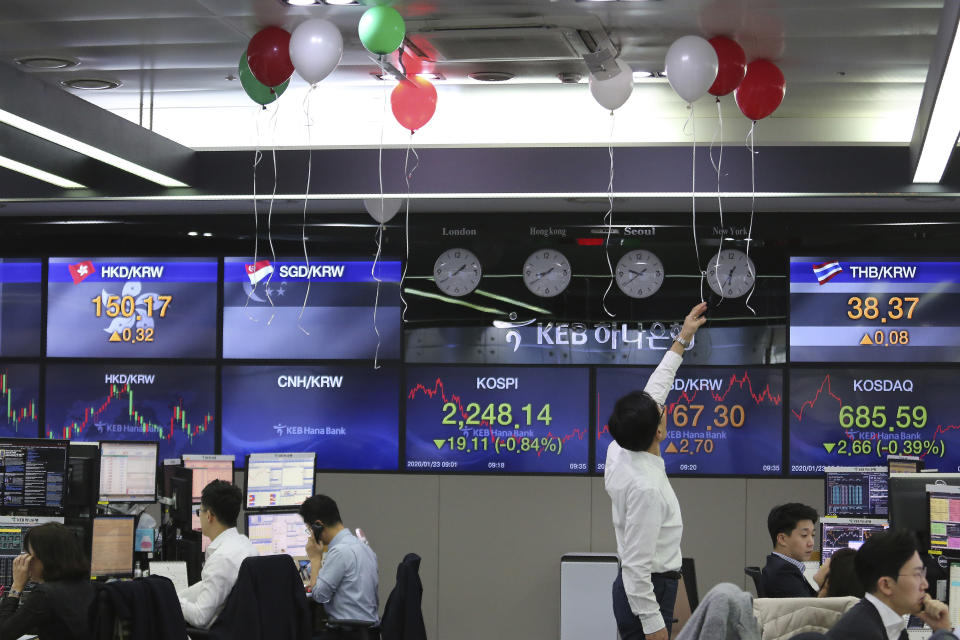 A currency trader touches balloons displayed in celebration of receiving an award for last year's performance at the foreign exchange dealing room of the KEB Hana Bank headquarters in Seoul, South Korea, Thursday, Jan. 23, 2020. Asian shares are mostly higher as health authorities around the world move to monitor and contain a deadly virus outbreak in China and keep it from spreading globally. (AP Photo/Ahn Young-joon)