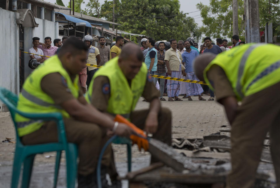 Police officers collect evidence from a site of a gun battle between troops and suspected Islamist militants as neighbors gather to watch in Kalmunai, Sri Lanka, Sunday, April 28, 2019. Police in Ampara showed The Associated Press on Sunday the explosives, chemicals and Islamic State flag they recovered from the site of one security force raid in the region as Sri Lanka's Catholics celebrated at televised Mass in the safety of their homes. (AP Photo/Gemunu Amarasinghe)