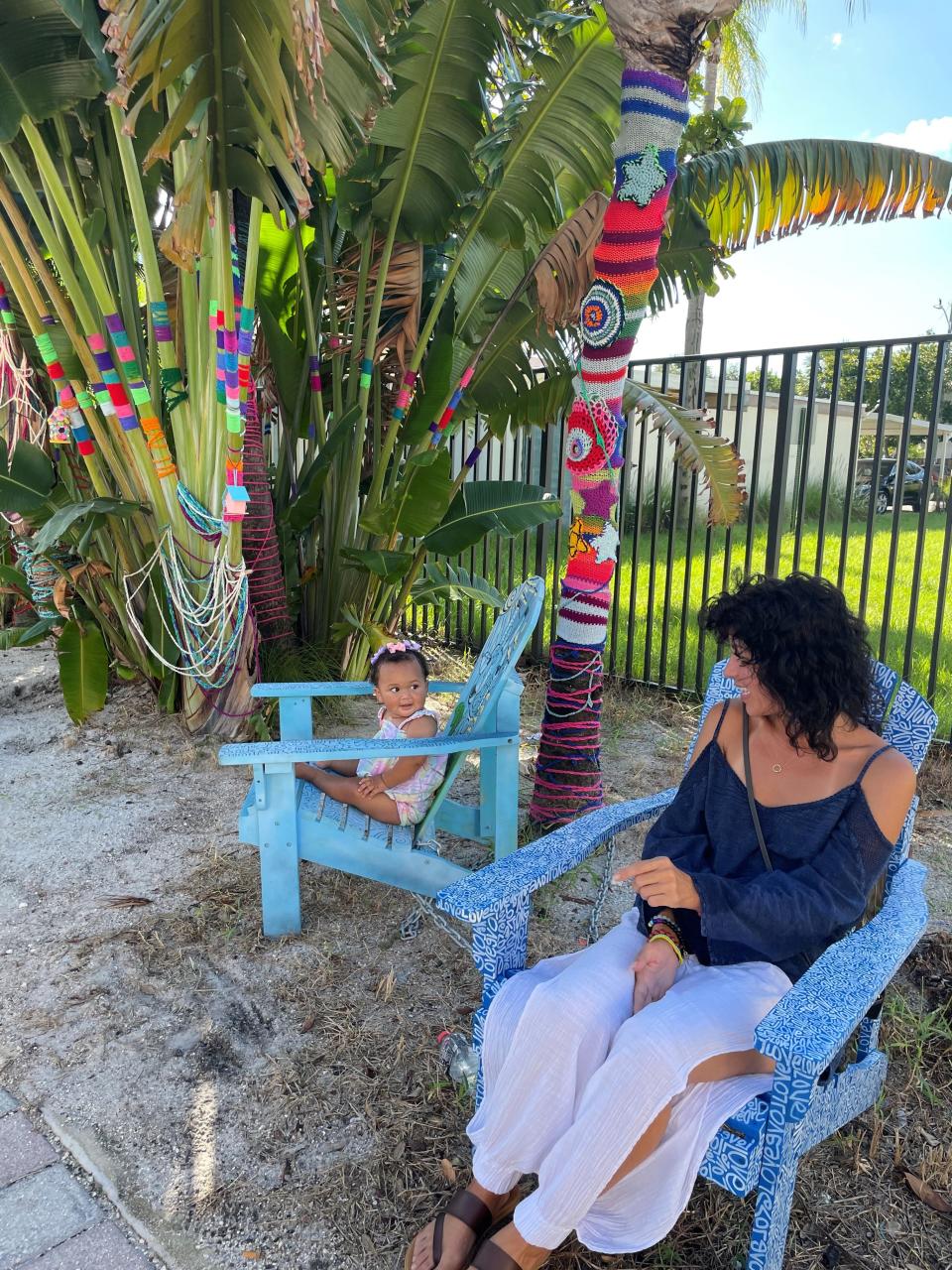 Take a break and make a friend left to right -- Isabella Clark and Lake Worth Beach resident Amy La Ve meet and admire the Andirondack chairs painted by local artists, in front of the Yarn Bomb Installation by Milena Arrango.