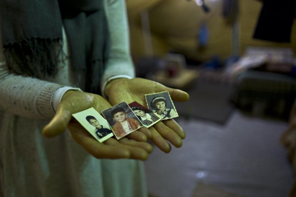 In this Tuesday, Jan. 17, 2017 photo, Sahar Dargzini, 40, a Syrian refugee from Baghdad street in Damascus, shows photographs of her children when they were young, from right, Amal who currently is 24 and lives in Norway, Dania who currently is 26 and lives in Turkey, Mohyeddin, whose currently 15 and lives in Sweden and Salahudin whose currently 20 and lives in Sweden, at her tent in Kalochori refugee camp on the outskirts of the northern Greek city of Thessaloniki. "I love keeping my children pictures with me all the times, they will always remain my children, I hope they will allow me to go to Norway and be with my daughter and see my granddaughter Mirna." Sahar said. (AP Photo/Muhammed Muheisen)