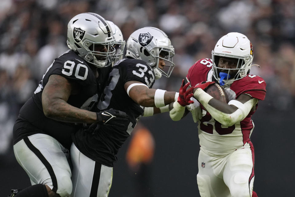 Arizona Cardinals running back Eno Benjamin, right, runs past Las Vegas Raiders safety Roderic Teamer (33) and defensive tackle Johnathan Hankins (90) during the second half of an NFL football game Sunday, Sept. 18, 2022, in Las Vegas. (AP Photo/John Locher)