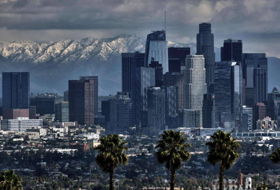 Storm clouds and snowfall are seen over the San Gabriel mountain range behind downtown Los Angeles on Sunday, Feb. 26, 2023. (AP Photo/Richard Vogel)