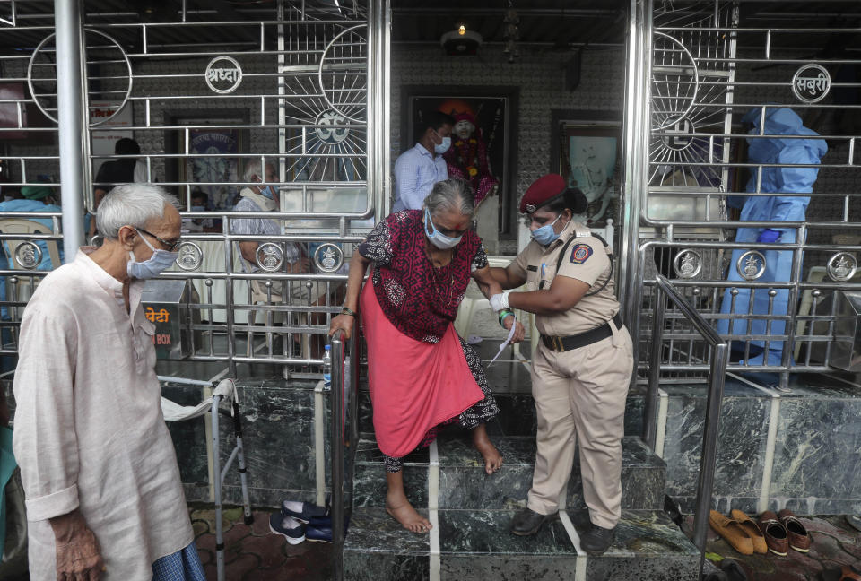 An elderly woman walks down a flight of stairs, helped by a policewoman, after she gave her swab sample, at a temple in Mumbai, India, Saturday, July 18, 2020. India crossed 1 million coronavirus cases on Friday, third only to the United States and Brazil, prompting concerns about its readiness to confront an inevitable surge that could overwhelm hospitals and test the country's feeble health care system. (AP Photo/Rafiq Maqbool)