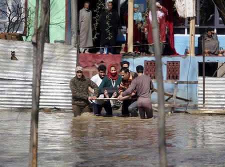 An ailing woman is carried on a wooden plank to a safer place from her partially submerged house after incessant rains in Srinagar March 30, 2015. REUTERS/Danish Ismail