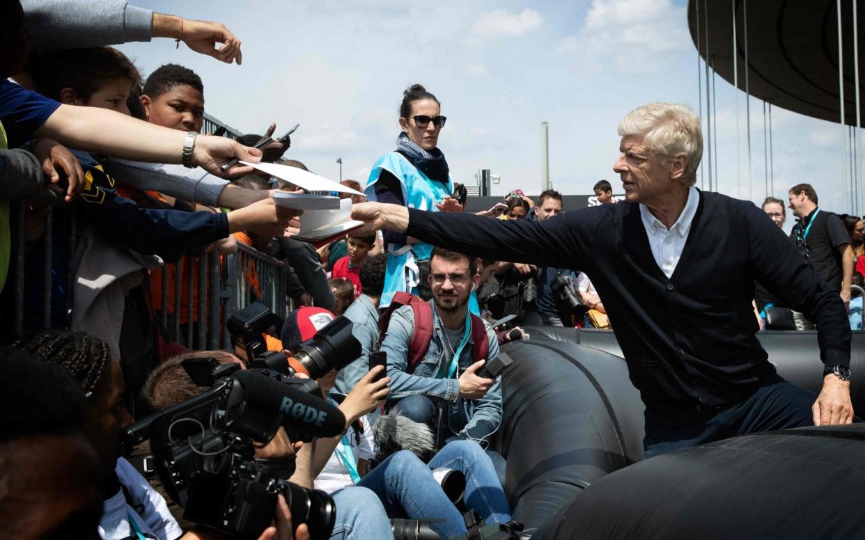 Arsene Wenger signs autographs after a football match for a children's association at the Stade de France this week - AFP