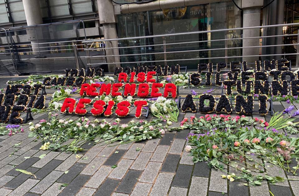 Flowers form a slogan reading “Rise, remember, resist