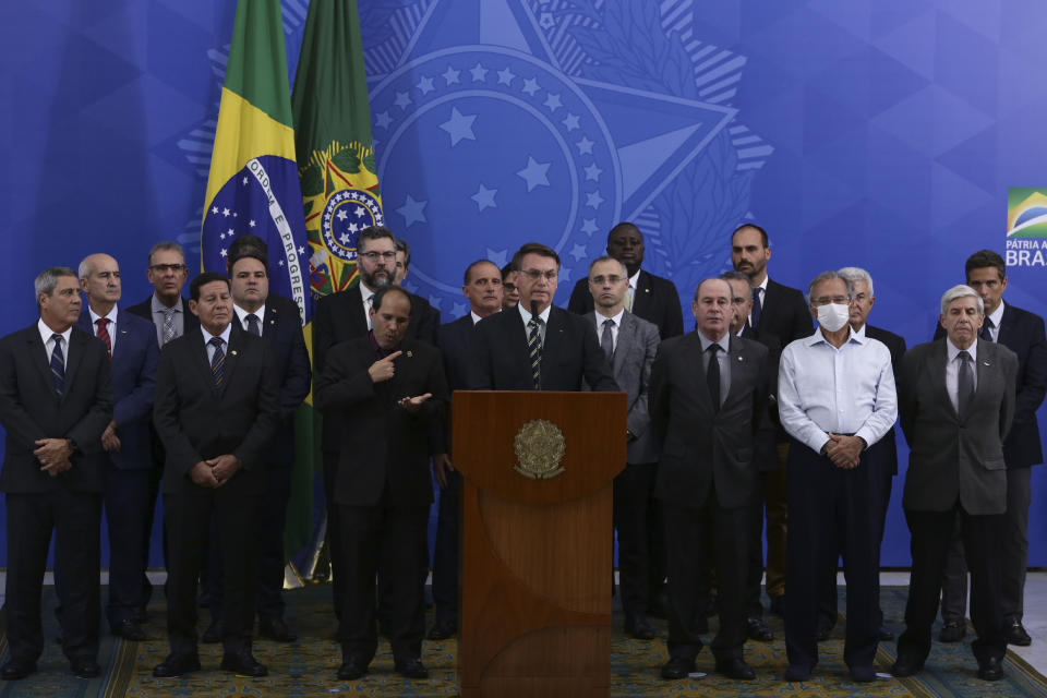 Accompanied by his Cabinet, Brazil's President Jair Bolsonaro speaks during a press conference on the resignation of Justice Minister Sergio Moro, at the Planalto Presidential Palace in Brasilia, Brazil, Friday, April 24, 2020. Moro, who became popular as a crusader against corruption, resigned on Friday, alleging political interference in the federal police force. (AP Photo/Eraldo Peres)