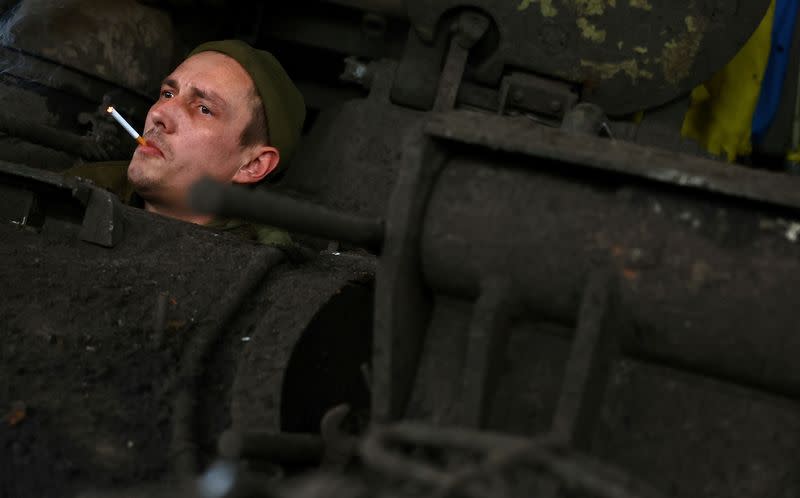 Ukrainian tank crew members wait for mechanics to maintain their tank after a mission in Bakhmut region