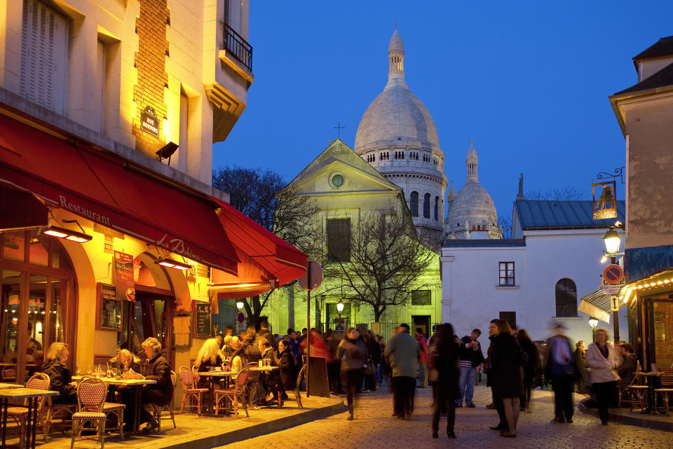 A bar with people sitting outdoors at night.