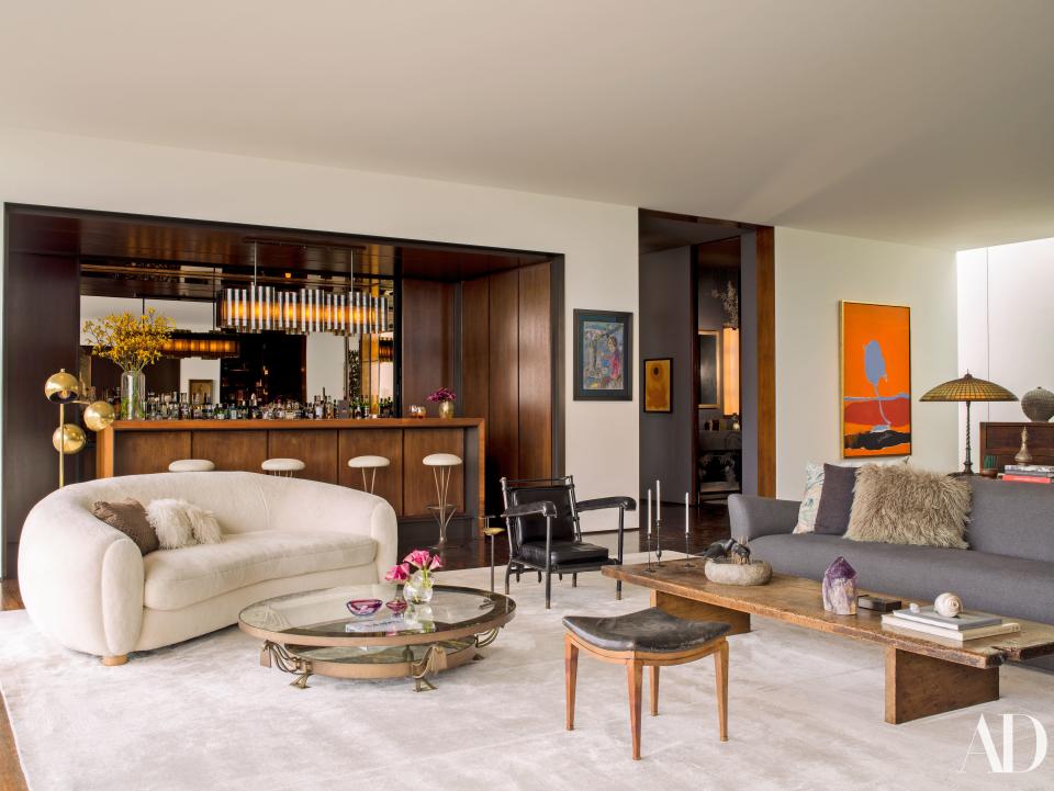 The living room is outfitted with 20th-century classics. Jean Royère polar bear sofa; Arturo Pani cocktail table; leather-wrapped armchair by Jacques Adnet; Piet Hein for Fritz Hansen barstools from Wyeth in a Holly Hunt leather. Custom walnut, bronze, and mica bar by Shadley; painting on far right by Robert Motherwell.