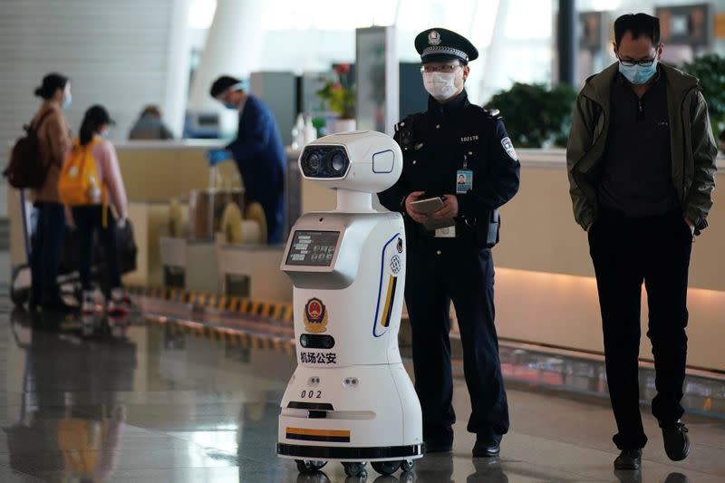 Police officer stands next to a police robot at the Wuhan Tianhe International Airport