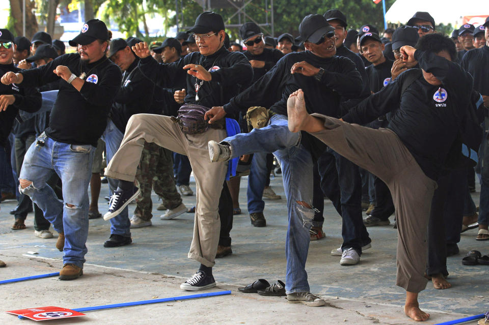 In this April 3, 2014 photo, black-clad supporters of Thai Prime Minister Yingluck Shinawatra perform in a Thai kickboxing exercise in Udon Thani province, Thailand. Following the directions of a trainer on a nearby stage, they fended off kicks and practiced footwork to loud speakers blaring music typically heard at a Thai kickboxing stadium. It was was part of a two-day training course for farmers, laborers and others in the heart of pro-government “Red Shirt” country - Thailand’s rural, poor north and northeast. (AP Photo/Sakchai Lalit)