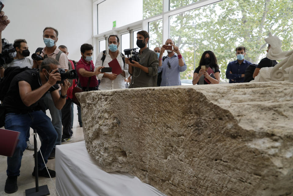 Photographers take pictures during the presentation to the press of an archeological finding emerged during the excavations at a Mausoleum in Rome, Friday, July 16, 2021. The monumental pomerial stone is dating back to Roman Emperor Claudio and was used to mark the ‘pomerium’ the sacred boundaries of the ‘Urbe’, the city of Rome, during the Roman empire. (AP Photo/Domenico Stinellis)