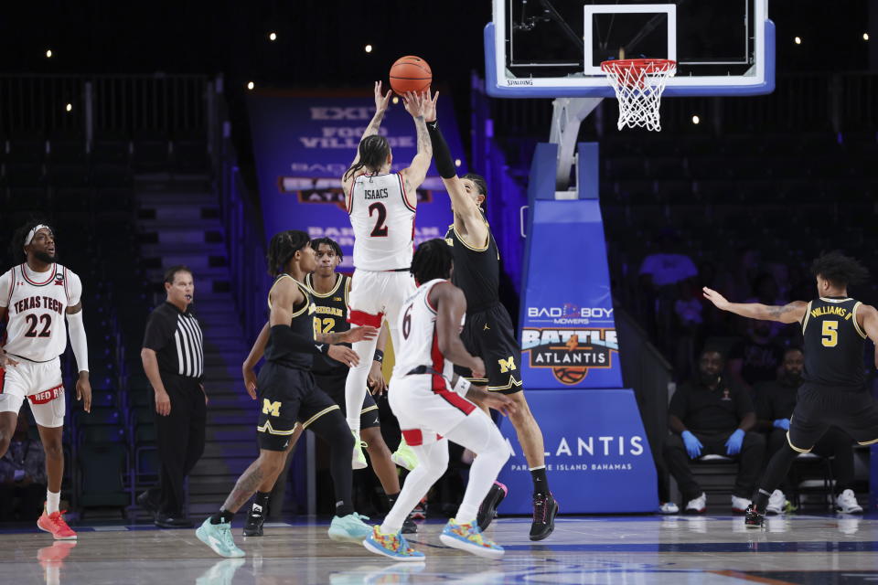 In a photo provided by Bahamas Visual Services, Texas Tech's Pop Isaacs (2) shoots as Michigan's Olivier Nkamhoua, center right, blocks during an NCAA college basketball game in the Battle 4 Atlantis at Paradise Island, Bahamas, Friday, Nov. 24, 2023. (Tim Aylen/Bahamas Visual Services via AP)