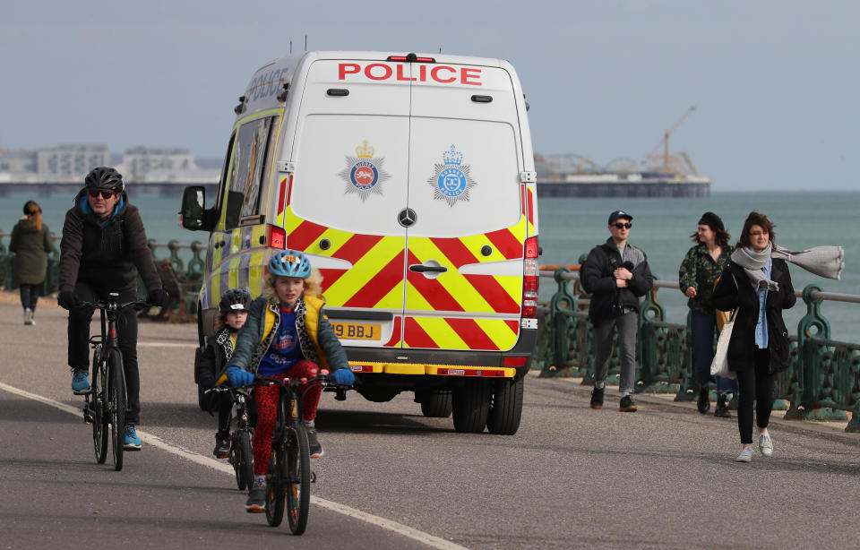 A Sussex Police van moves amongst people walking along the promenade in Brighton as the UK continues in lockdown to help curb the spread of the coronavirus.