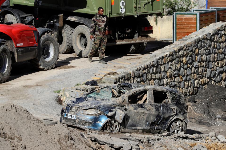 A service man walks past a car destroyed following heavy rains and floods in Breil-sur-Roya, southern France.