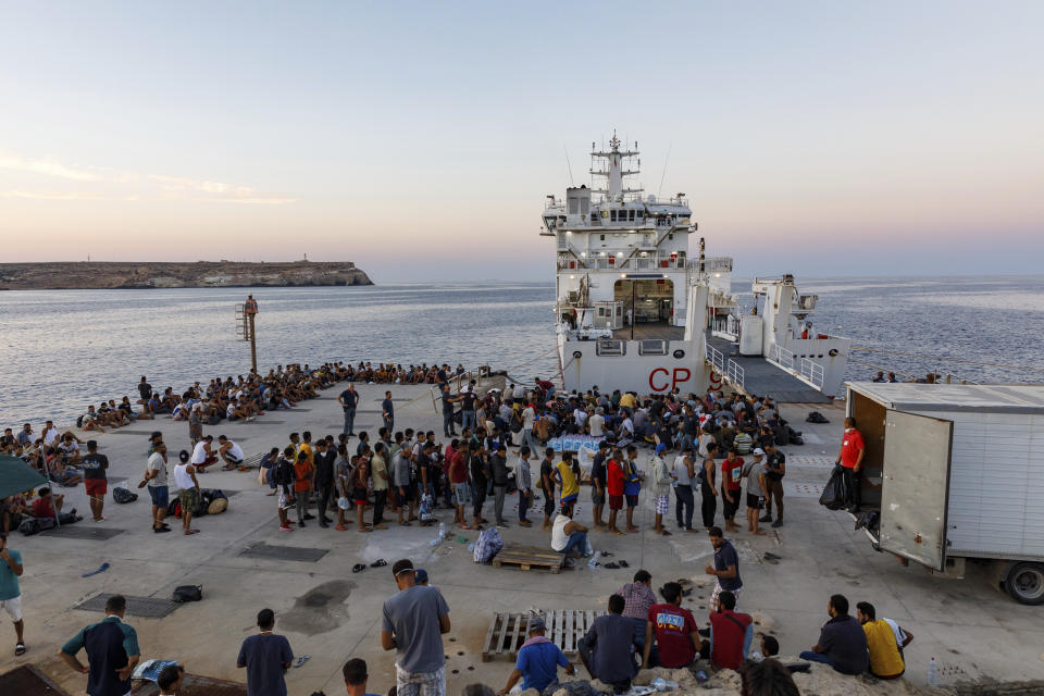 Migrants wait to board an Italian Coast Guard ship in the Sicilian Island of Lampedusa, Italy, Wednesday, Aug. 3, 2022. The migrants reception center on the island, which is also a summertime tourist destination, reached more than 1,500 people in a space designed, by his count, for 357. (AP Photo/David Lohmueller)